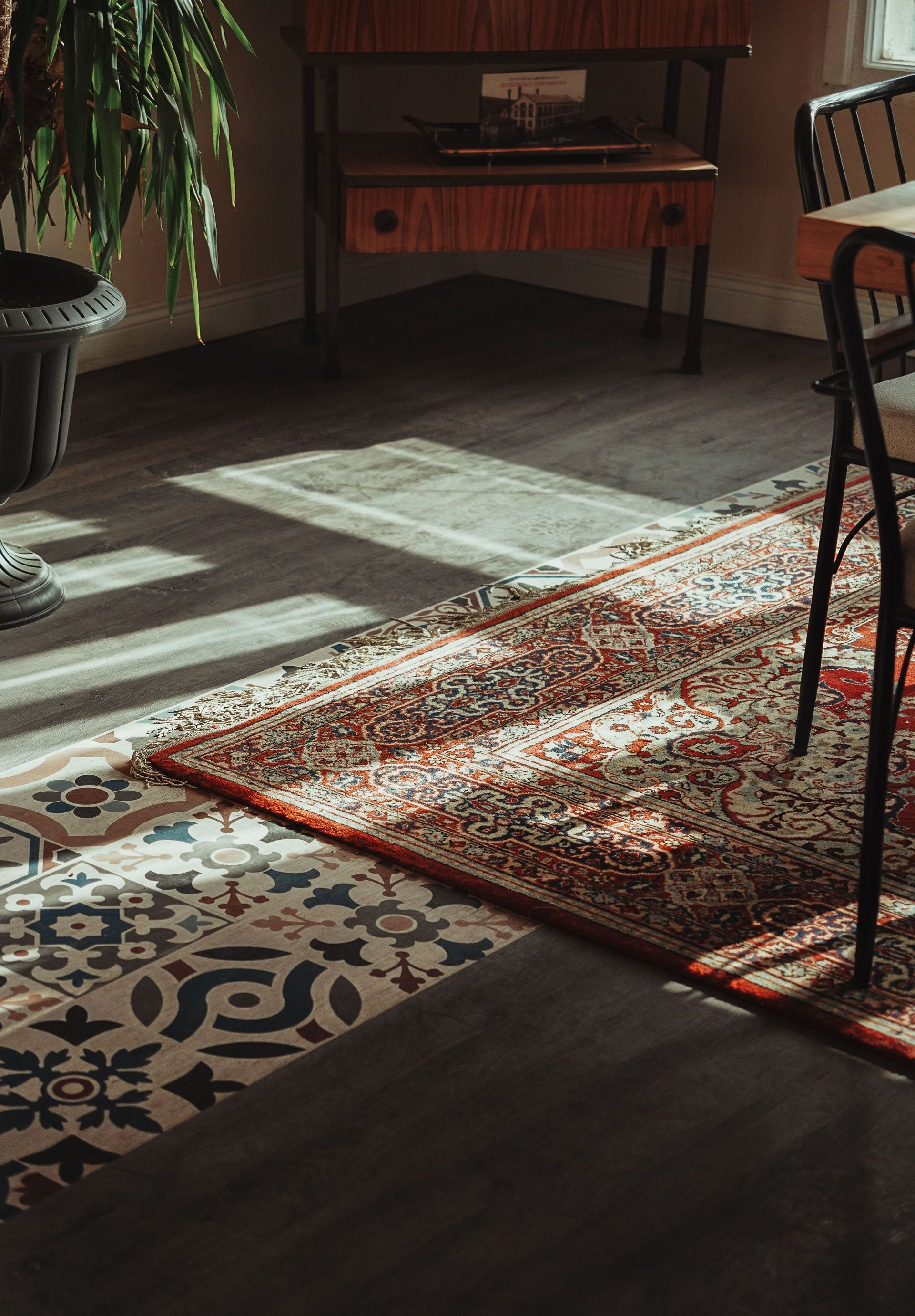 Cozy sunlit room featuring a vintage rug, patterned tiles, and modern decor, creating a warm ambiance.